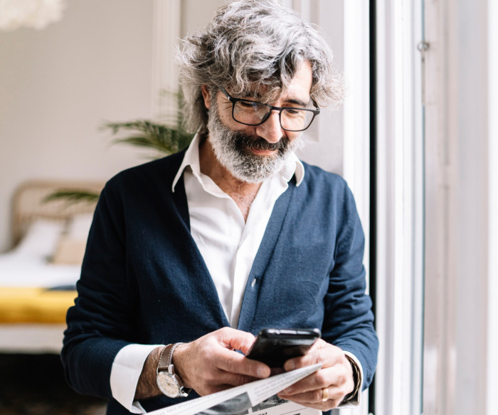 Un homme aux cheveux blancs regarde son téléphone portable.