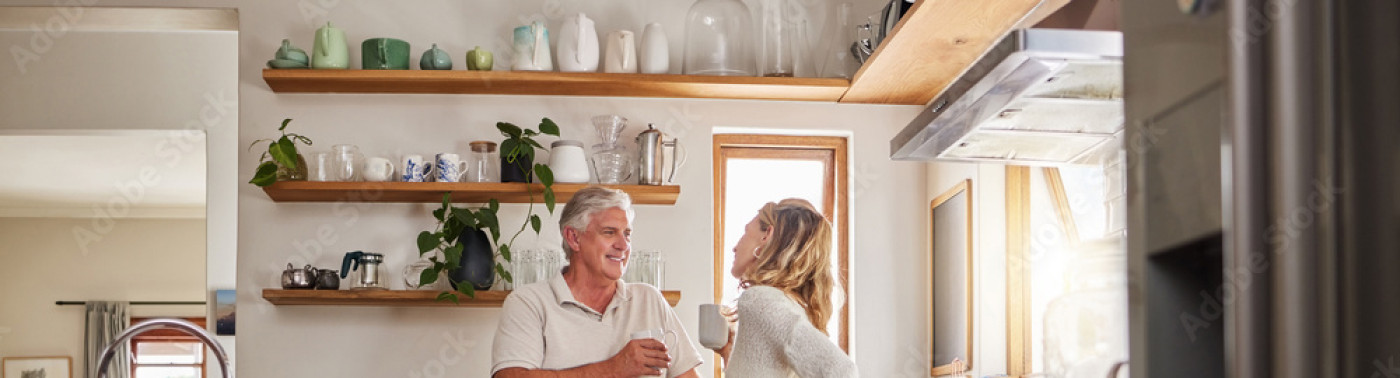 Un couple debout boit un verre dans leur cuisine.