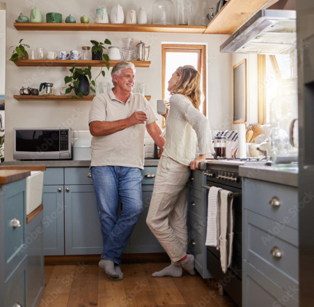 Un couple debout boit un verre dans leur cuisine.