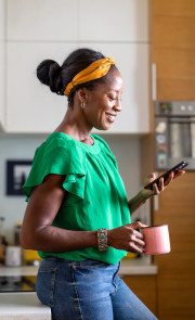 Une femme dans la cuisine regarde son téléphone portable